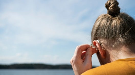 Kvinne sett bakfra som justerer høreapparat