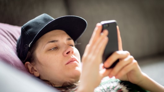 Ung person med caps som ser alvorlig på en mobiltelefon