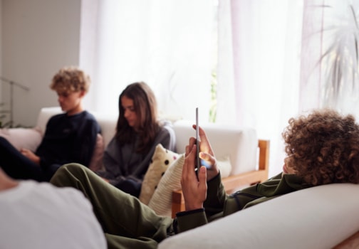 Gruppe unge som sitter inne i en sofa med telefon i handa